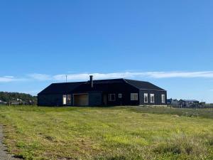 LeñaduraHermosa Casa con vista al Estrecho de Magallanes的田野旁的黑房子