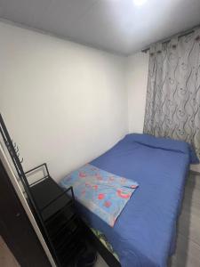a small bedroom with a blue bed and a window at Apartamento Vacacional con Piscina in Ibagué