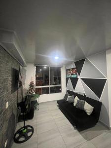 a living room with a black couch and a window at Apartamento Vacacional con Piscina in Ibagué