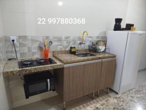 uma pequena cozinha com pia e geladeira em Loft aconchegante Estou em Arraial em Arraial do Cabo mais 11 fotografias