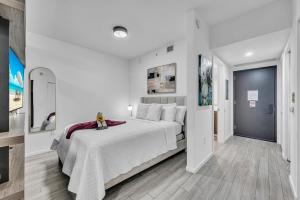 a white bedroom with a large bed and a hallway at Modern Studio City Views in Miami