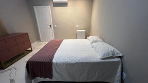 ein Schlafzimmer mit einem Bett, einer Kommode und einer Tür in der Unterkunft Studio no Centro da Cidade in Parauapebas