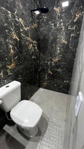 ein Badezimmer mit einem weißen WC und einer schwarzen Marmorwand in der Unterkunft Studio no Centro da Cidade in Parauapebas