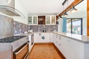 una cucina con mobili bianchi e un forno a piano cottura di Goulburn Stay with Garden Views & Comfort a Goulburn Altre 8 foto