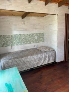 a small bed in a room with wooden walls at Cabaña Cica in Punta Del Diablo