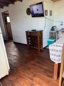 a room with a tv and a wooden floor at Cabaña Cica in Punta Del Diablo