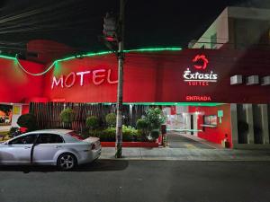 een auto die 's nachts voor een motel geparkeerd staat bij Motel Éxtasis in Mexico-Stad
