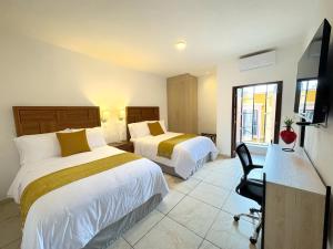 a hotel room with two beds and a television at Hotel Casa KARLOTTA in San Miguel de Allende