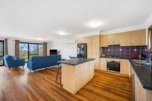 eine große Küche mit Holzschränken und blauen Stühlen in der Unterkunft The Beachfront in Lake Cathie