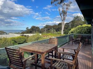 een houten tafel en stoelen op een terras met uitzicht op de oceaan bij Lorne Beach House in Lorne