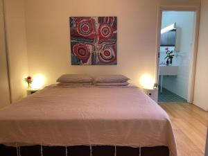 een slaapkamer met een bed en een schilderij aan de muur bij Lorne Beach House in Lorne