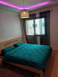 una camera da letto con un letto verde con una luce rosa di Mohemmadia a Mohammedia