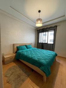 una camera da letto con un letto con un piumone verde e una finestra di Mohemmadia a Mohammedia