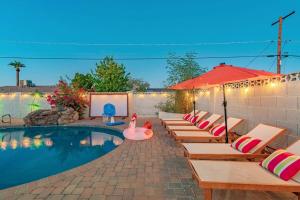 a swimming pool with lounge chairs and an umbrella at Ella Oasis Heated Pool Hot Tub Near Old Town in Scottsdale