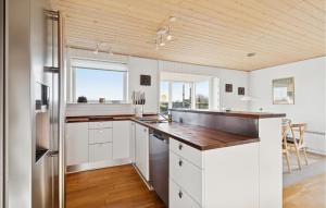 eine Küche mit weißen Schränken und einer Holzdecke in der Unterkunft Amazing Home In Ringkøbing With Sauna in Nørby