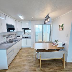 Una cocina con gabinetes blancos y una mesa de madera. en Ocean House PH, en Pohang