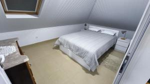 um quarto com uma cama branca com dois travesseiros em Banda Além Apartment by Mth em Tábua