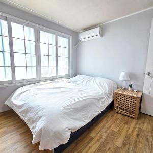 Un dormitorio con una cama blanca y dos ventanas. en Ocean House PH, en Pohang 10 fotos más