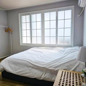 Una cama en un dormitorio con una ventana grande. en Ocean House PH, en Pohang