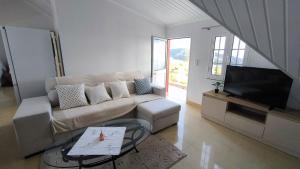 uma sala de estar com um sofá e uma TV de tela plana em Banda Além Apartment by Mth em Tábua