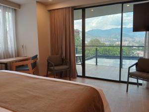Habitación de hotel con cama y balcón con vistas. en Hotel Rulay Medellin, en Medellín