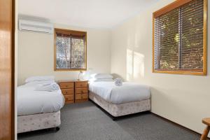 ジンダバインにあるMogul Lakeside - East Jindabyneのベッドルーム1室(ベッド2台、ドレッサー、窓2つ付)