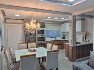 a kitchen and dining room with a white table and chairs at Casa com piscina, suite com hidro em Blumenau in Blumenau
