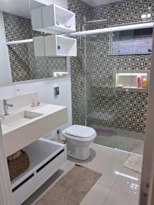 a white bathroom with a toilet and a sink at Casa com piscina, suite com hidro em Blumenau in Blumenau
