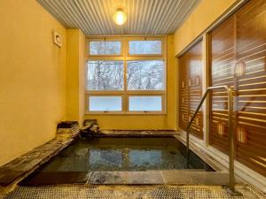 uma piscina de água num quarto com janela em 志賀 石の湯ホテル em Yamanouchi