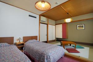 um quarto de hotel com duas camas e uma mesa em 志賀 石の湯ホテル em Yamanouchi mais 41 fotografias