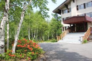 um prédio com escadas e flores em um quintal em 志賀 石の湯ホテル em Yamanouchi