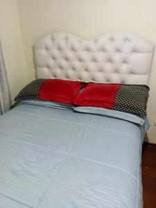 un letto con testiera bianca e cuscini rossi di Departamento en la cuida de cuenca todo amoblado capacidad 10 personas a Cuenca