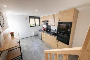 a kitchen with wooden cabinets and a black appliance at Duplex Cosy - Moderne - 15min Versailles in Saint-Forget +21 photos