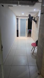 um corredor com uma sala de paredes brancas e uma cadeira vermelha em Tropical Suítes-Próx Praça da República em Belém