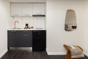 una cucina con elettrodomestici neri e armadietti bianchi di Tsimiski View CityCenter Boutique Suite - By Nuvia Domus a Salonicco