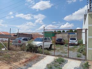 a fence with cars parked in a parking lot at KITNET - Completa e Individual - Pousada Itapetininga in Itapetininga