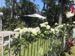 a white fence with flowers and an umbrella at Sunrise Cove in Airlie Beach