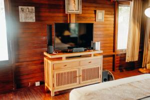 Una sala de estar con un televisor en una pared de madera. en Kubu He Mamatica, en Tianyar