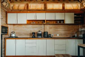 cocina con armarios blancos y pared de madera en Kubu He Mamatica, en Tianyar