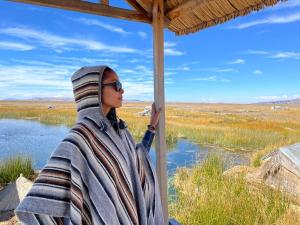 普诺Titicaca Lodge uros的一位裹着毯子的女人眺望着湖面。