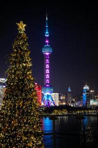 Un árbol de Navidad frente a una ciudad por la noche. en Banyantree Shanghai On the Bund - Tales rooftop bar boasts a jaw-dropping panoramic vista, en Shanghái