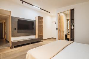 a bedroom with a bed and a flat screen tv at Green House Hotel in Salento