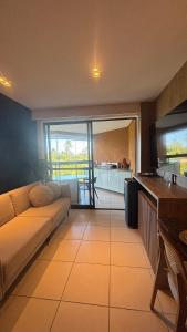 a living room with a couch and a kitchen at Apt beira-mar no Eco Resort Praia dos Carneiros in Praia dos Carneiros