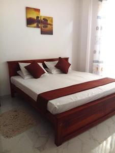 a bedroom with a wooden bed with white sheets at CrossWay Inn Thalawathugoda in Talawatugoda