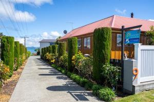 una acera junto a un edificio con árboles y flores en Harbourside Getaway, en One Tree Point