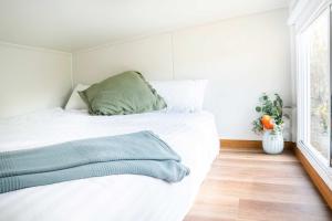 een slaapkamer met een wit bed met een groen kussen bij Hidden Camp's Loft House by Tiny Away in Kanighan
