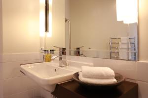 a white bathroom with a sink and a mirror at The Dome Boutique Apartments in Napier