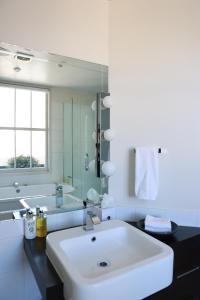 a bathroom with a large white sink and a tub at The Dome Boutique Apartments in Napier