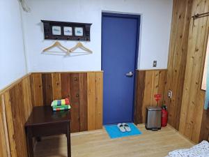 统营市Antwerp Guesthouse的一间设有蓝色门和一张桌子的房间