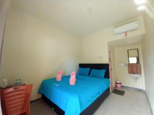 a bedroom with a blue bed with pink shoes on it at Stella Dell Mare Homestay and Tour in Labuan Bajo